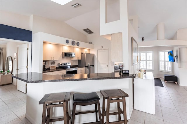 kitchen featuring light tile patterned flooring, kitchen peninsula, and appliances with stainless steel finishes