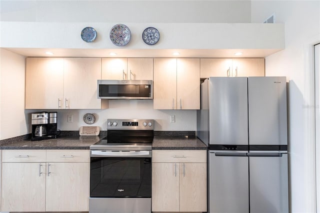 kitchen with stainless steel appliances, light brown cabinetry, and dark stone counters