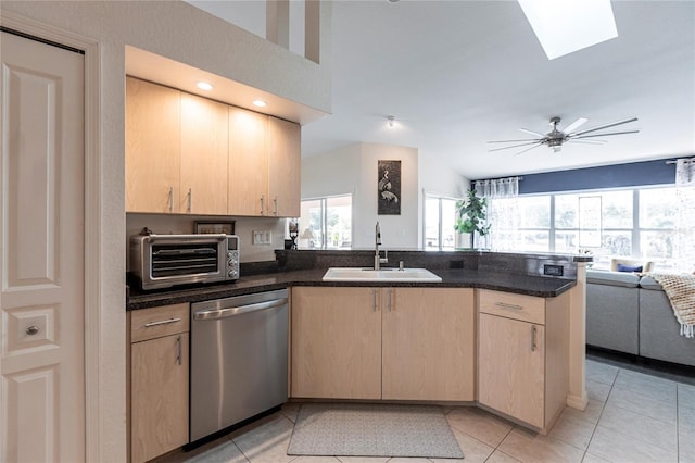 kitchen with light brown cabinetry, sink, stainless steel dishwasher, and kitchen peninsula