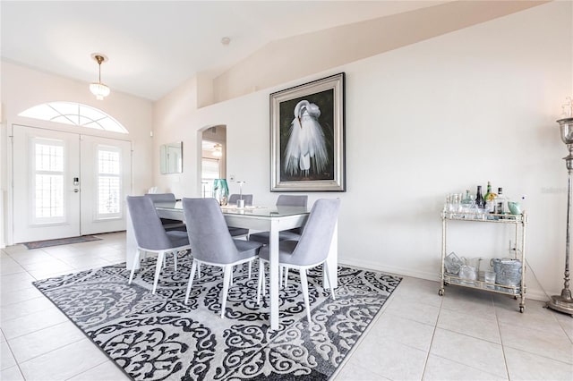 dining room featuring light tile patterned floors, vaulted ceiling, and french doors