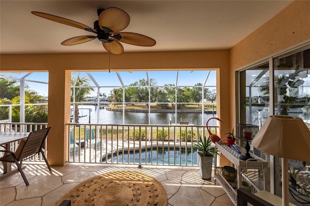 sunroom with ceiling fan and a water view