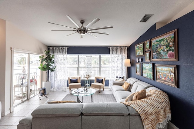 living room with lofted ceiling, light tile patterned floors, a textured ceiling, and ceiling fan