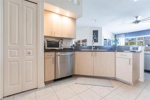 kitchen with light brown cabinetry, sink, light tile patterned floors, stainless steel dishwasher, and ceiling fan