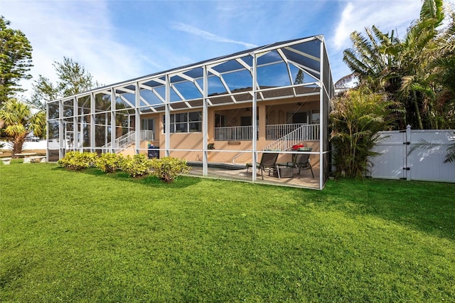 back of property with a patio, a yard, and glass enclosure