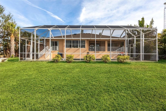 back of house featuring a lawn and glass enclosure