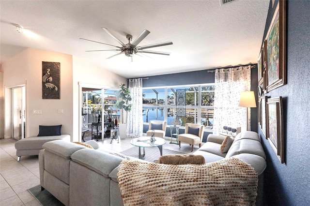 tiled living room with a water view, a textured ceiling, lofted ceiling, and ceiling fan