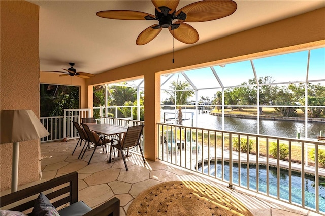 sunroom with a water view and ceiling fan