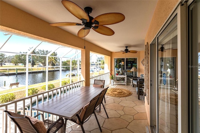 sunroom / solarium featuring ceiling fan and a water view