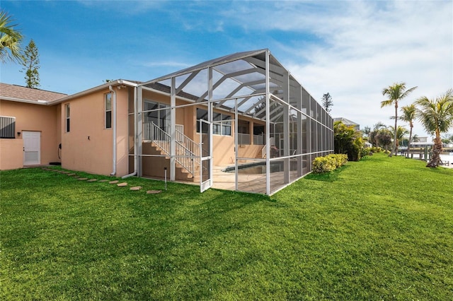 rear view of house with a patio, glass enclosure, and a lawn