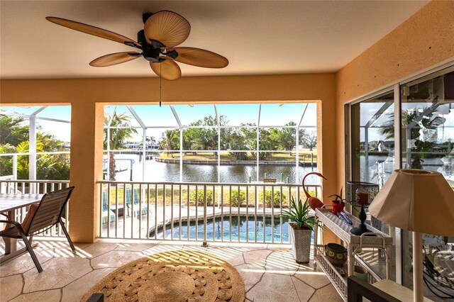 sunroom featuring a healthy amount of sunlight, ceiling fan, and a water view