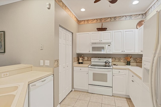 kitchen featuring sink, white cabinets, light tile patterned floors, crown molding, and white appliances