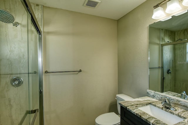 bathroom with walk in shower, vanity, and toilet