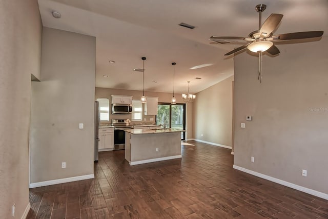 kitchen with a kitchen island, ceiling fan with notable chandelier, pendant lighting, white cabinets, and stainless steel appliances