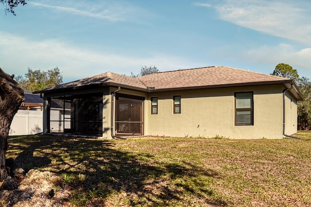 back of property with a sunroom and a lawn