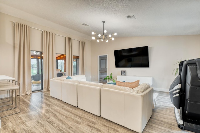 living room featuring lofted ceiling, a chandelier, light hardwood / wood-style floors, and a textured ceiling