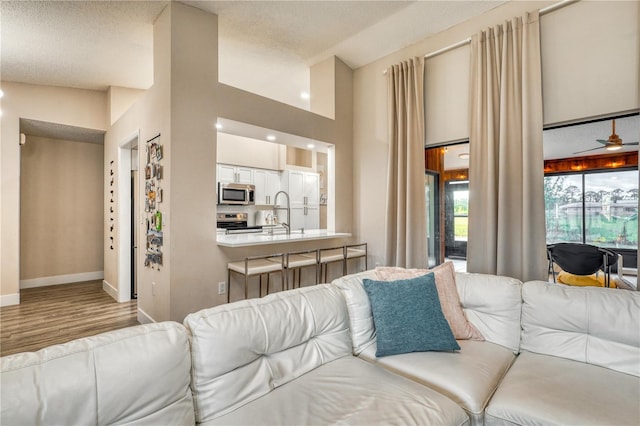 living room with sink, ceiling fan, and light wood-type flooring