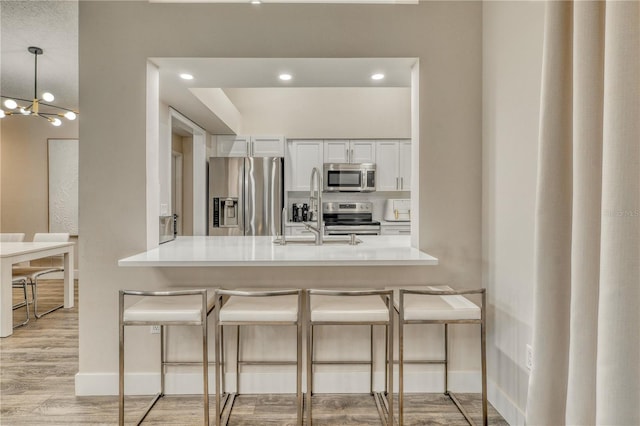 kitchen featuring a breakfast bar, appliances with stainless steel finishes, kitchen peninsula, and white cabinets