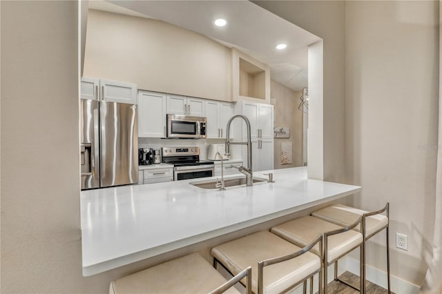 kitchen with a breakfast bar area, stainless steel appliances, tasteful backsplash, white cabinets, and kitchen peninsula