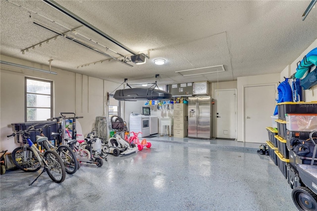 garage with a garage door opener, sink, stainless steel fridge, and independent washer and dryer