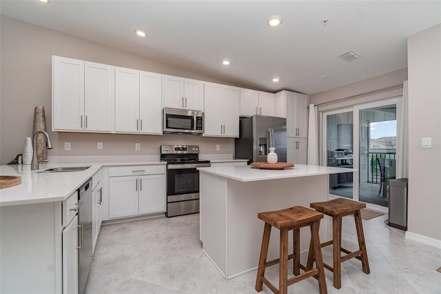 kitchen featuring white cabinetry, lofted ceiling, sink, a kitchen breakfast bar, and stainless steel appliances