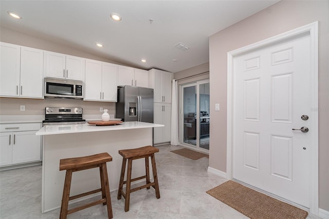 kitchen with lofted ceiling, a kitchen island, stainless steel appliances, white cabinets, and a kitchen bar