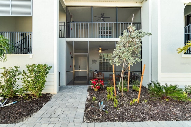 view of exterior entry featuring ceiling fan and a balcony