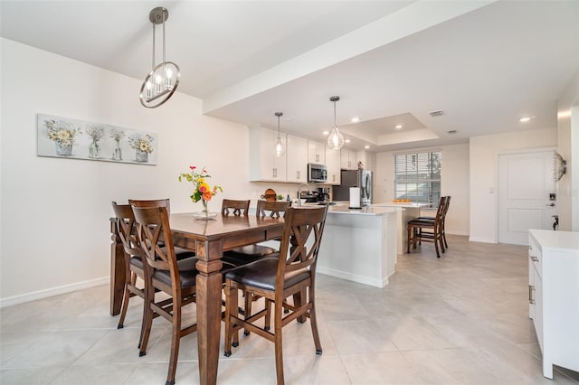 dining room featuring a raised ceiling and light tile patterned floors