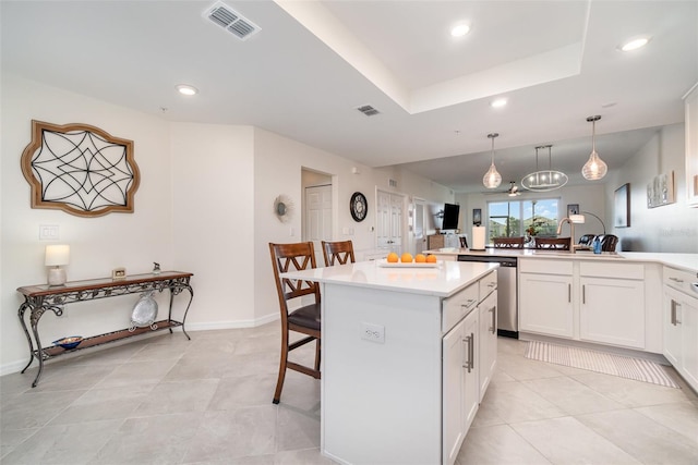 kitchen with sink, a breakfast bar area, white cabinetry, hanging light fixtures, and stainless steel dishwasher