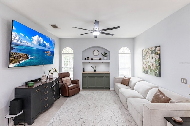 living room with built in shelves, light tile patterned flooring, and ceiling fan