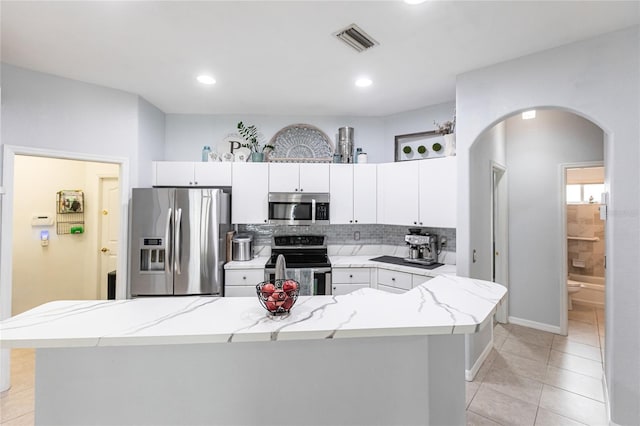 kitchen featuring light stone counters, white cabinetry, decorative backsplash, and appliances with stainless steel finishes