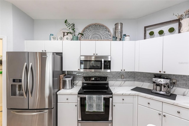 kitchen with light stone counters, white cabinets, decorative backsplash, and stainless steel appliances