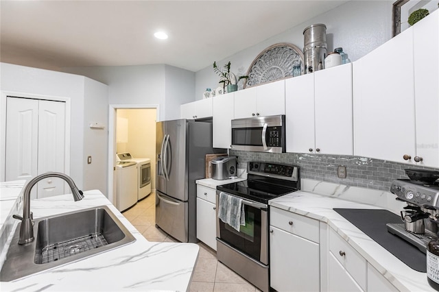 kitchen featuring sink, white cabinetry, washing machine and dryer, and stainless steel appliances