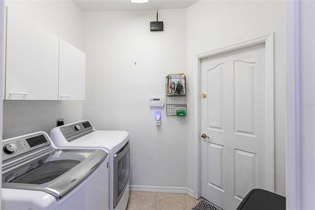 laundry room featuring cabinets, light tile patterned floors, and washing machine and clothes dryer