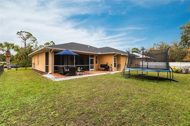 back of house with a patio area, a yard, and a trampoline