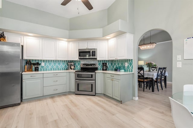 kitchen with ceiling fan, white cabinets, decorative light fixtures, a high ceiling, and stainless steel appliances