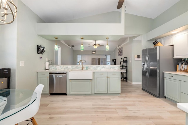 kitchen with vaulted ceiling, sink, decorative light fixtures, light hardwood / wood-style floors, and stainless steel appliances