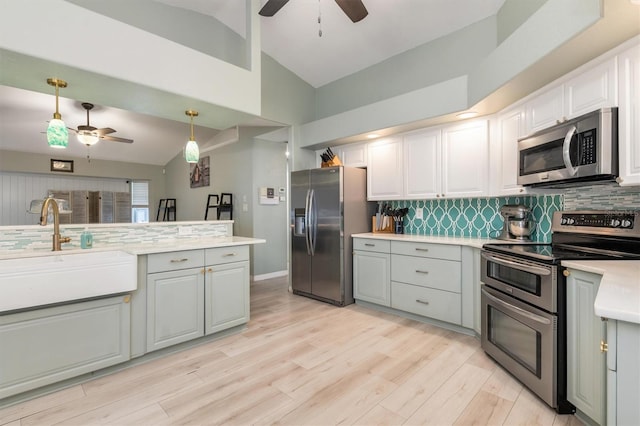 kitchen featuring lofted ceiling, white cabinets, pendant lighting, stainless steel appliances, and gray cabinets