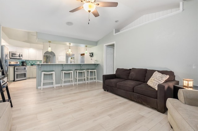 living room with light hardwood / wood-style floors, vaulted ceiling, and ceiling fan