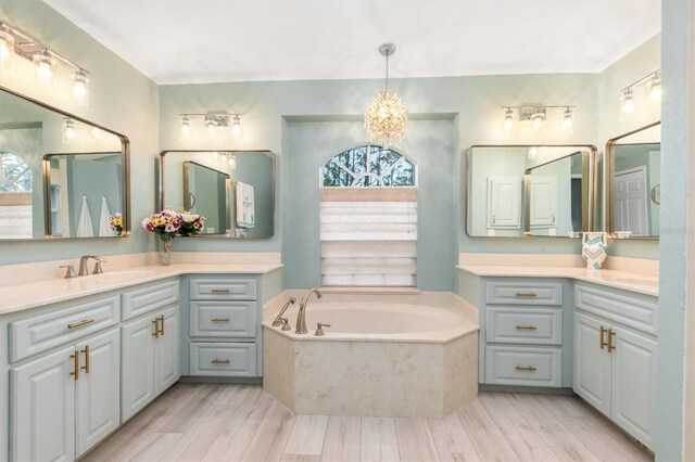 bathroom featuring vanity, a chandelier, tiled tub, and hardwood / wood-style floors