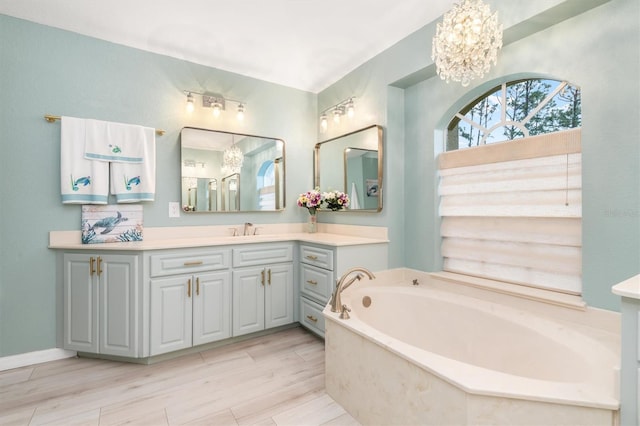 bathroom with hardwood / wood-style floors, vanity, a bathing tub, and a notable chandelier