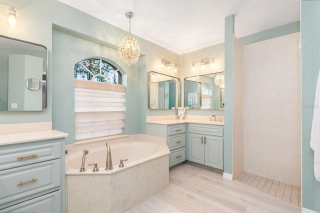 bathroom featuring wood-type flooring, vanity, independent shower and bath, and an inviting chandelier