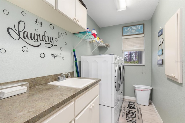 laundry area featuring sink, washing machine and clothes dryer, and light hardwood / wood-style floors