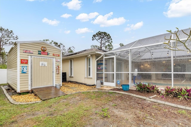 rear view of house with glass enclosure, a storage shed, and a swimming pool