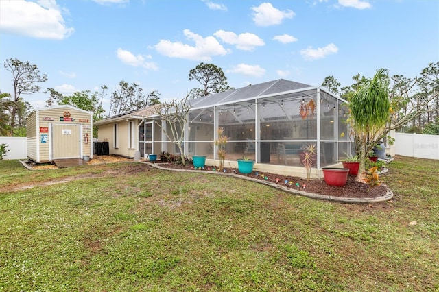 back of house with central air condition unit, a shed, a lanai, and a yard