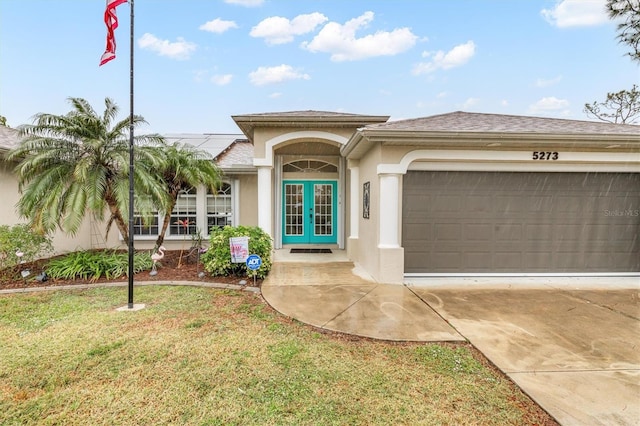 view of front facade featuring a garage, a front yard, and french doors