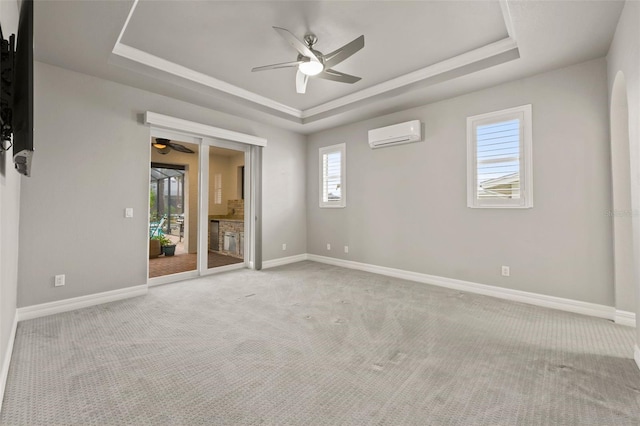 carpeted empty room featuring a wall mounted air conditioner, a raised ceiling, and ceiling fan