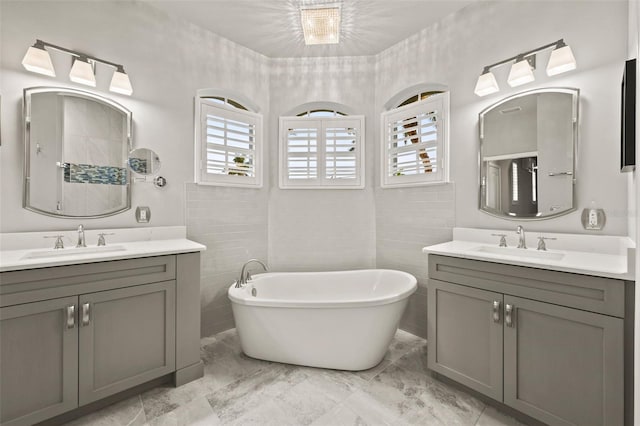 bathroom with a bathing tub, tile walls, and vanity