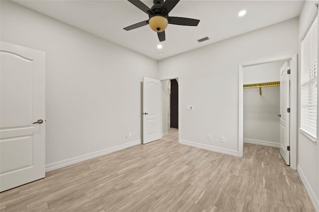 unfurnished bedroom featuring ceiling fan, a spacious closet, light wood-type flooring, and a closet