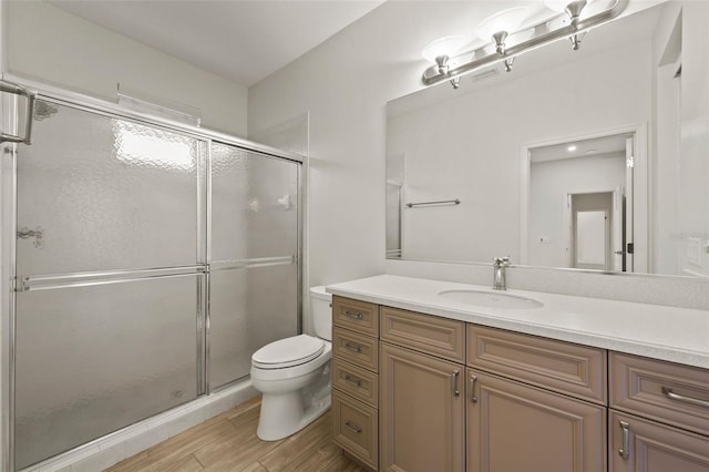 bathroom featuring vanity, hardwood / wood-style flooring, a shower with door, and toilet