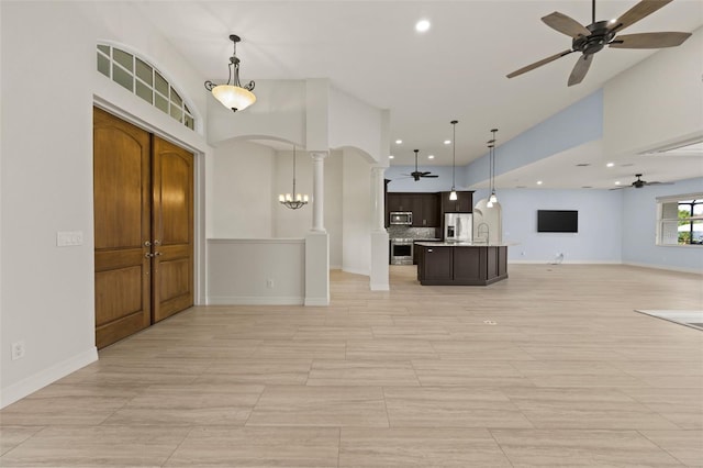 interior space with ceiling fan, decorative columns, and a high ceiling